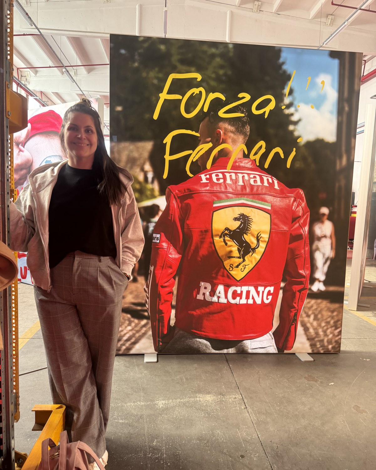 Standing on set at Maranello in front of a large Forza Ferrari backdrop inside the Ferrari facility.